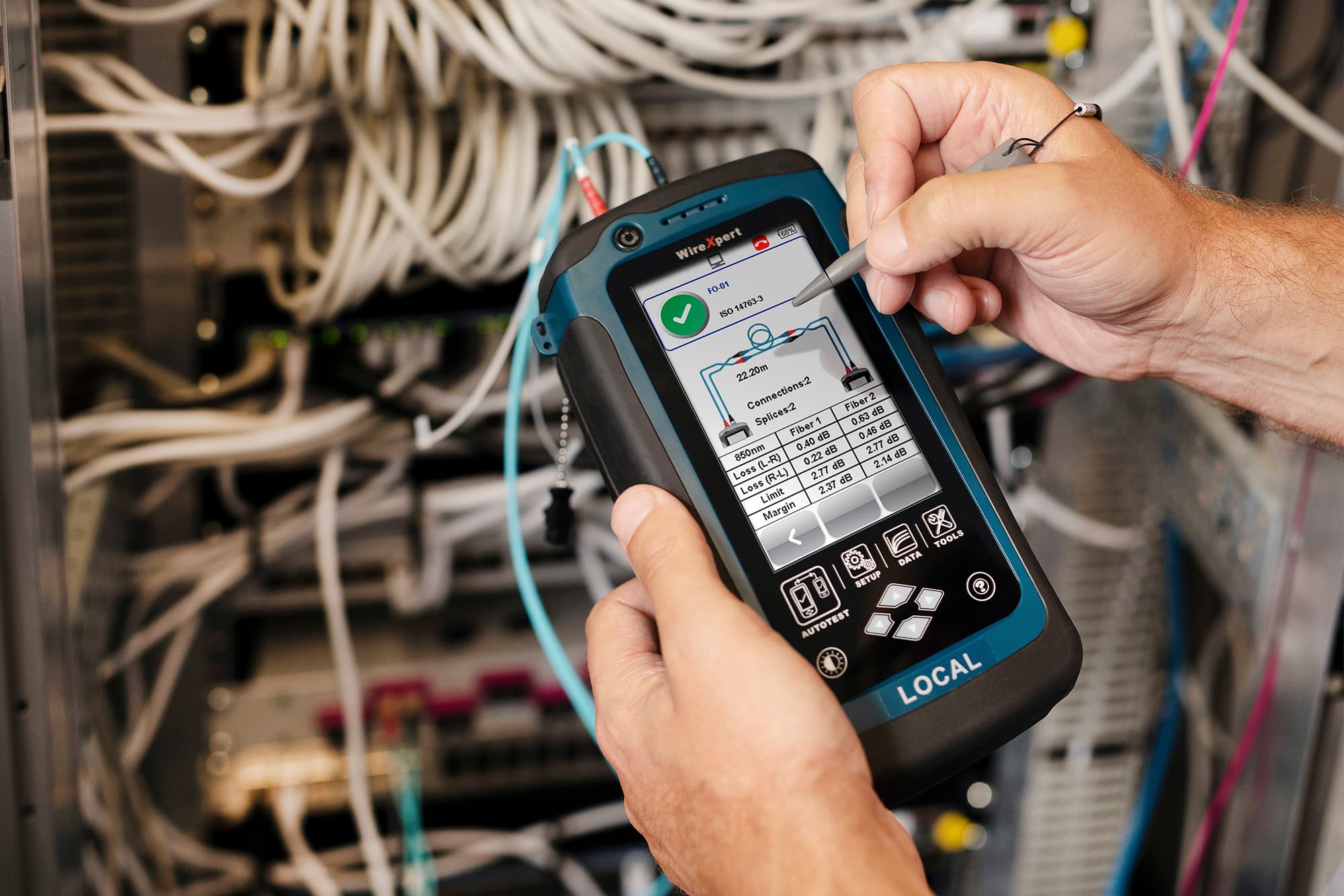 Technicus houdt professioneel meet- en testapparaat vast voor een serverrack